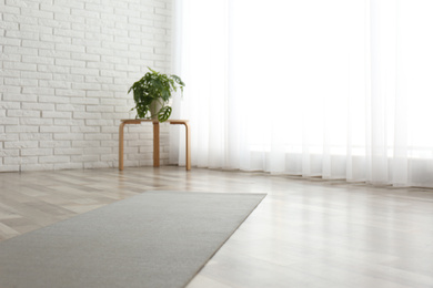 Unrolled grey yoga mat on floor in room