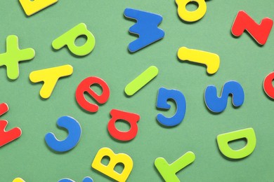 Photo of Learning alphabet. Magnetic letters on green background, flat lay