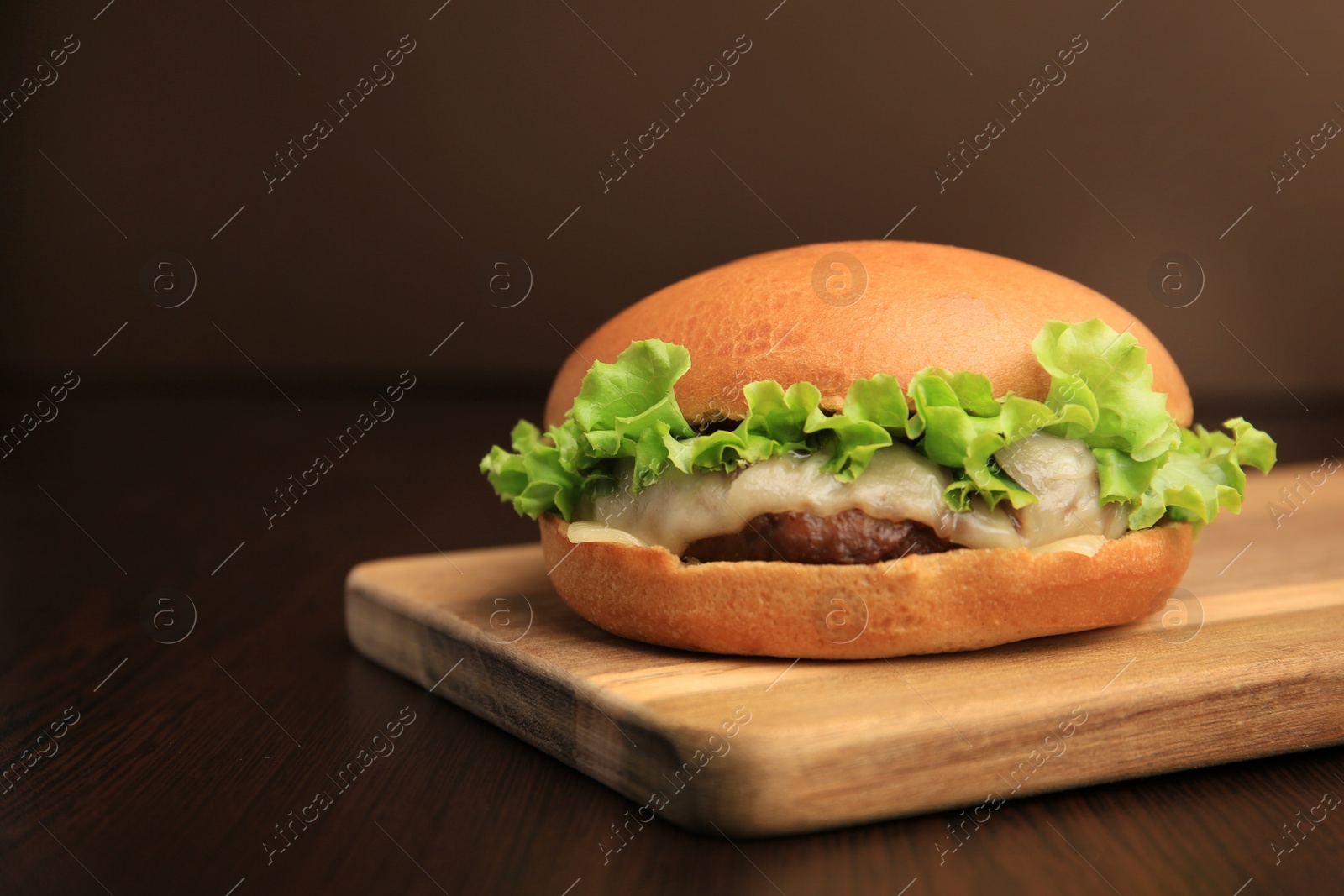 Photo of One tasty cheeseburger on wooden table. Space for text