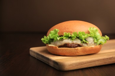 Photo of One tasty cheeseburger on wooden table. Space for text