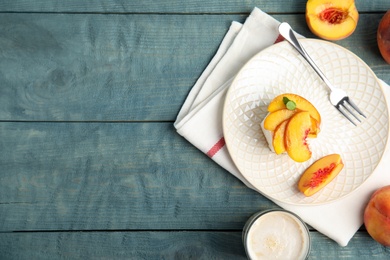 Photo of Delicious peach dessert on blue wooden table, flat lay. Space for text