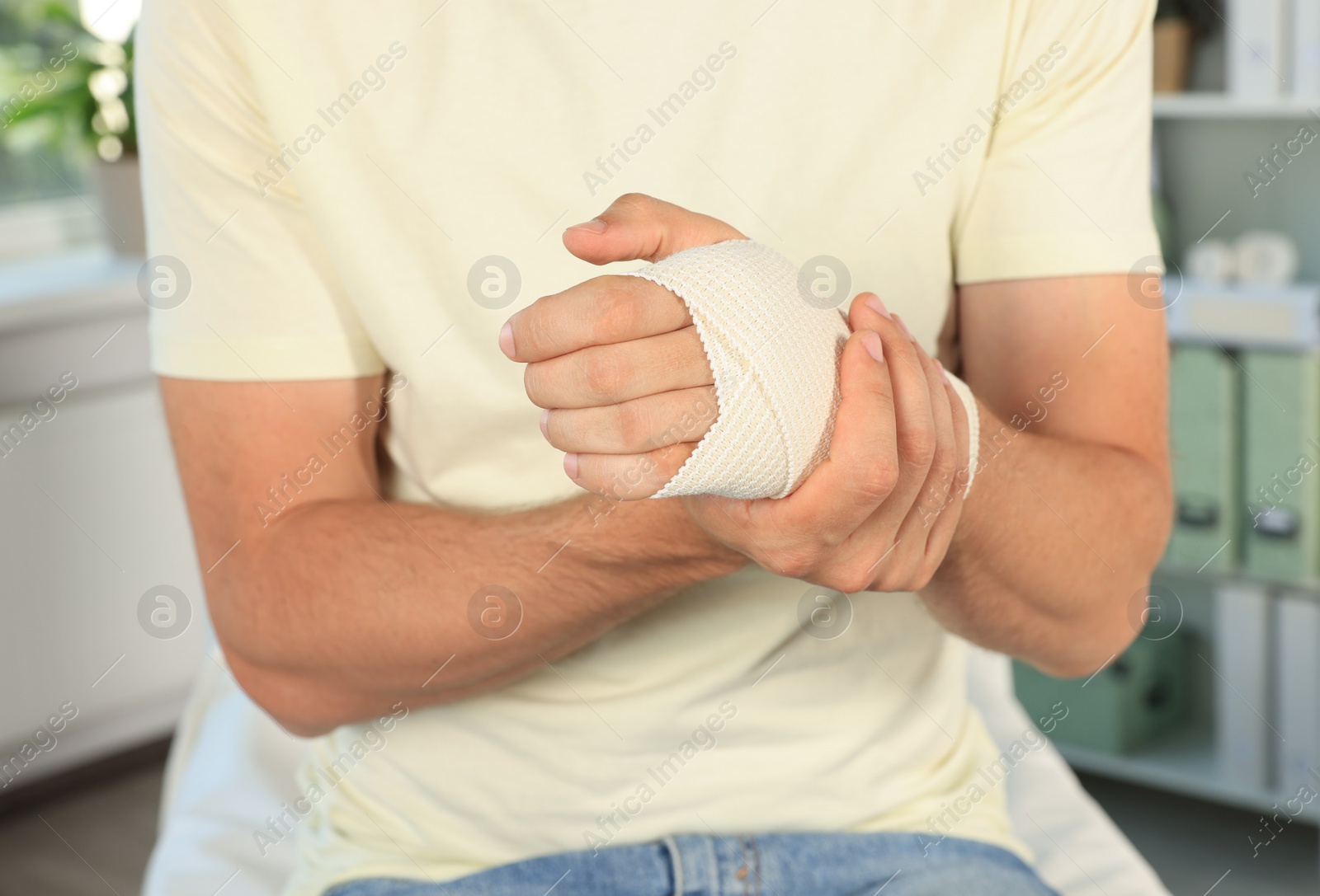 Photo of Man with hand wrapped in medical bandage at hospital, closeup