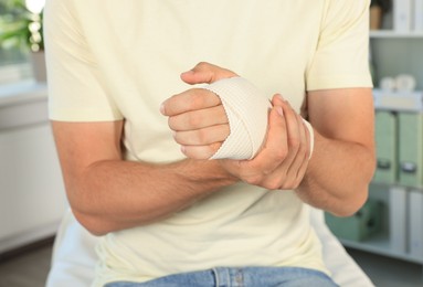 Man with hand wrapped in medical bandage at hospital, closeup