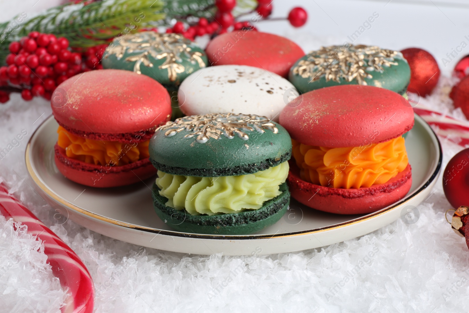 Photo of Beautifully decorated Christmas macarons, candy cane and festive decor on snow, closeup