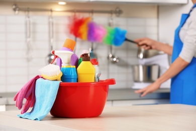 Set of cleaning supplies on table in kitchen. Space for text