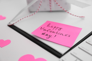 Photo of Memory sticker with phrase Happy Valentine's Day on clipboard at table, closeup