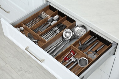 Photo of Open drawer with different utensils and cutlery in kitchen, above view
