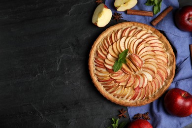 Flat lay composition with delicious homemade apple tart on black table. Space for text