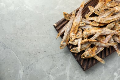 Photo of Delicious dried anchovies on light grey marble table, top view. Space for text