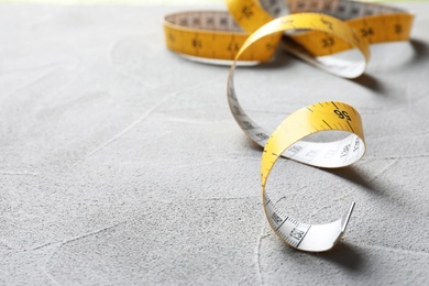 Photo of Measuring tape on grey background, closeup. Tailoring equipment