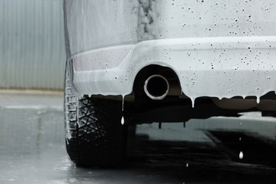 Auto with cleaning foam at car wash, closeup