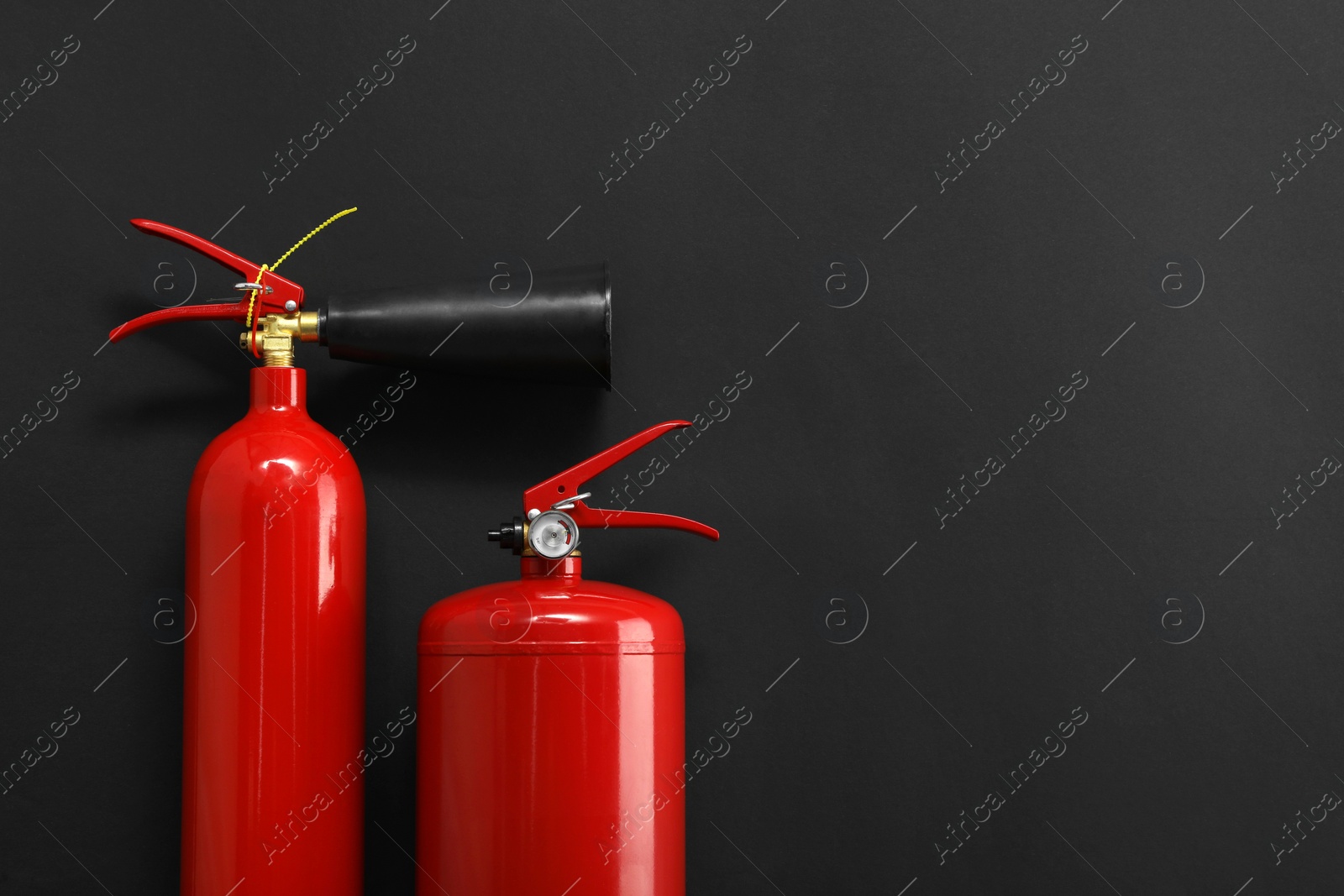 Photo of Fire extinguishers on black background, flat lay. Space for text