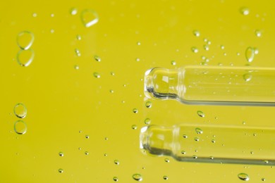Pipette near serum drops on beautiful mirror, closeup with space for text. Toned in yellow