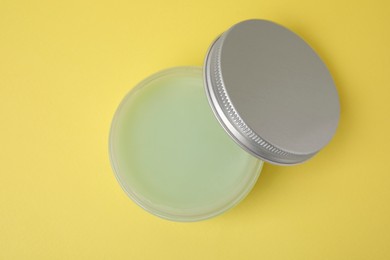 Jar of petroleum jelly on yellow background, top view