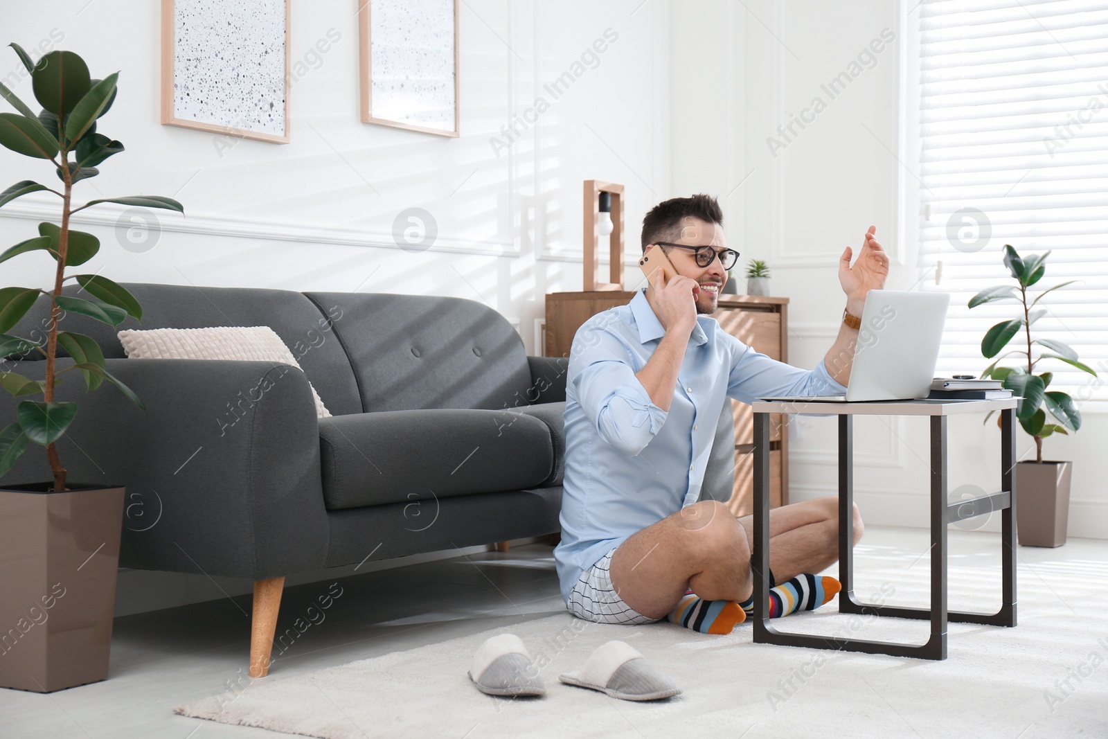 Photo of Businessman in shirt and underwear talking on phone during video call at home