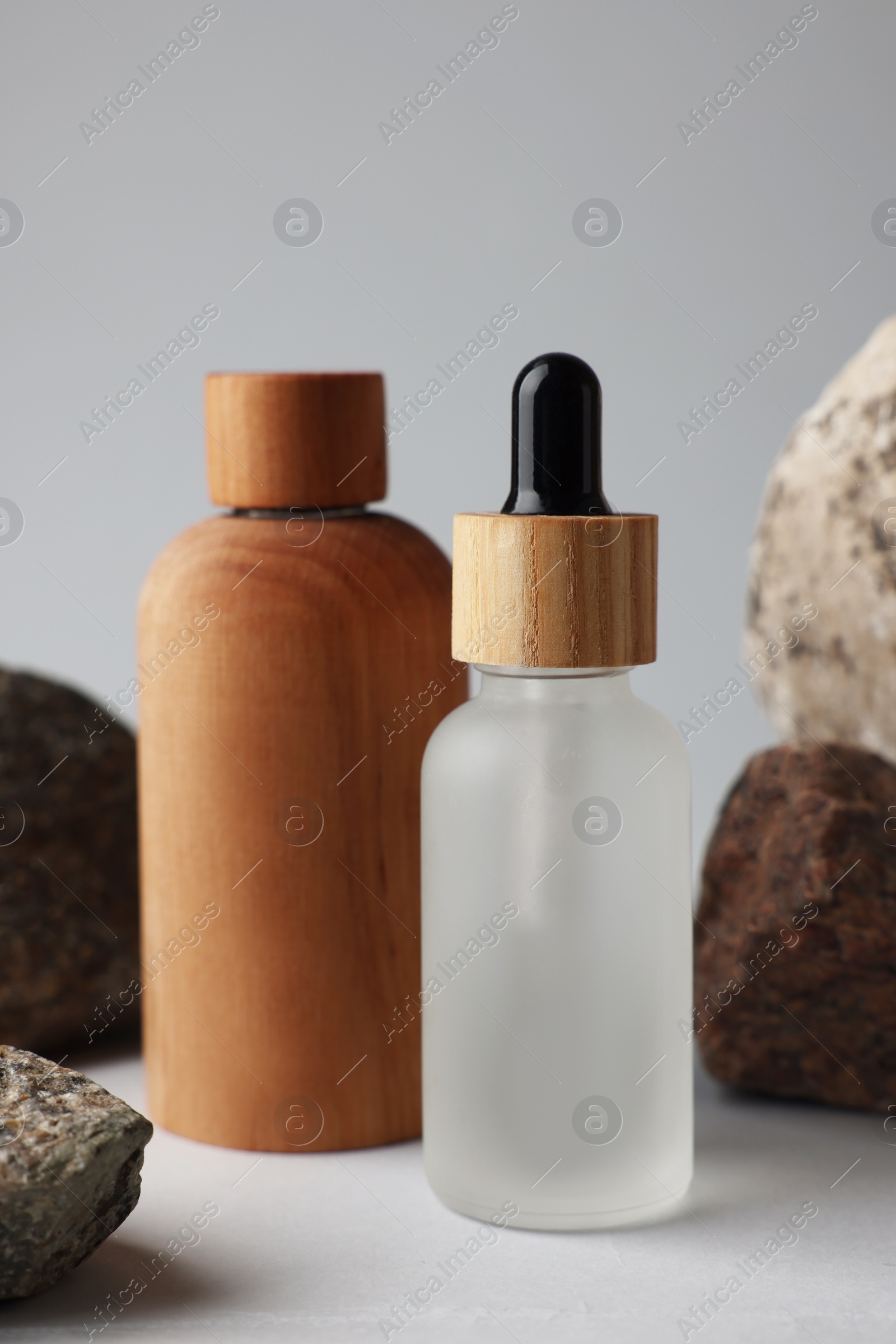 Photo of Different bottles and stones on grey background, closeup