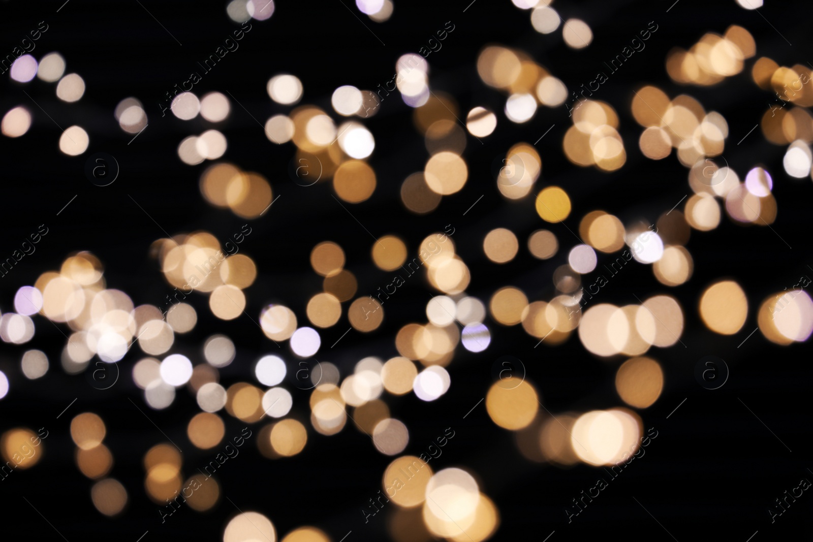 Photo of Golden and white blurred lights on black background. Bokeh effect