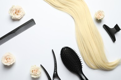 Flat lay composition with different hairdresser tools and flowers on white background, space for text