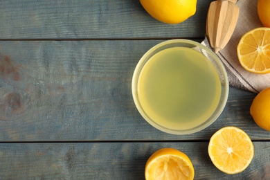 Photo of Freshly squeezed lemon juice on blue wooden table, flat lay. Space for text