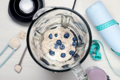 Photo of Making shake. Blueberries and powder in blender on white table, top view