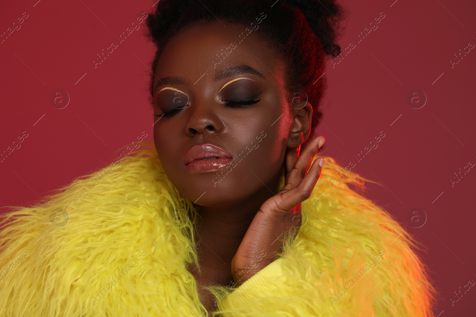 Photo of Fashionable portrait of beautiful woman with bright makeup on burgundy background