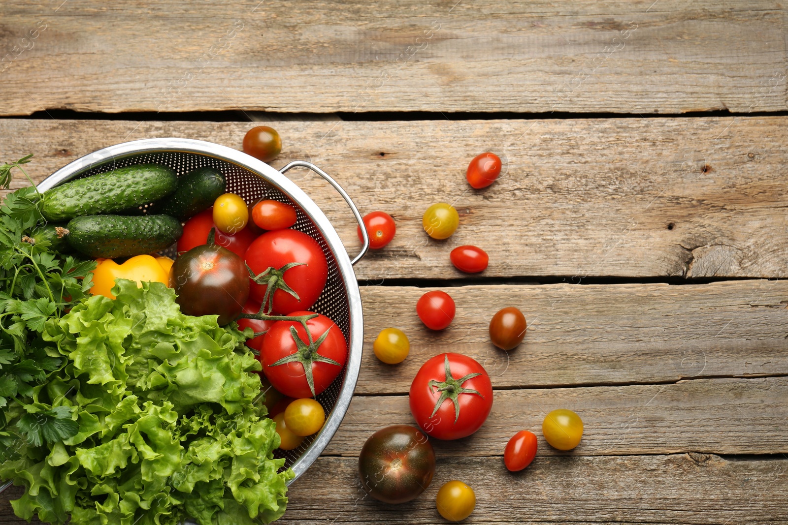 Photo of Fresh vegetables in colander on wooden table, flat lay. Space for text