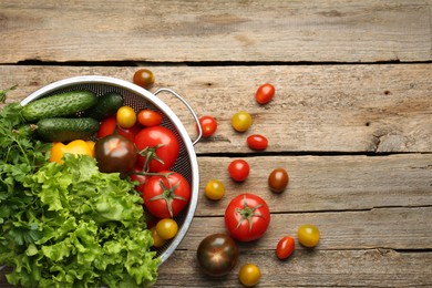 Photo of Fresh vegetables in colander on wooden table, flat lay. Space for text