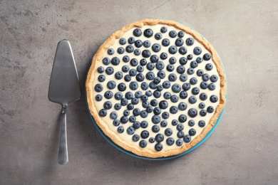 Photo of Tasty blueberry cake and pie server on gray background, top view