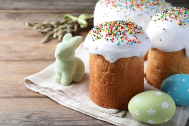 Photo of Beautiful Easter cakes with painted eggs and bunny on wooden table