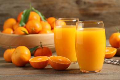 Photo of Glasses of fresh tangerine juice and fruits on wooden table