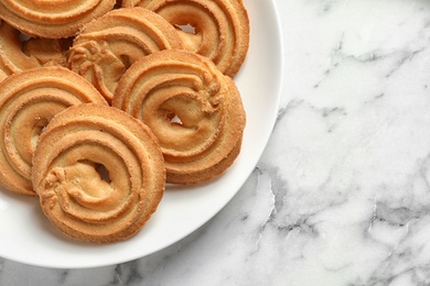 Photo of Plate with Danish butter cookies on marble table, top view. Space for text