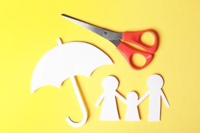 Photo of Paper silhouettes of family with umbrella and scissors on color background, flat lay. Life insurance concept