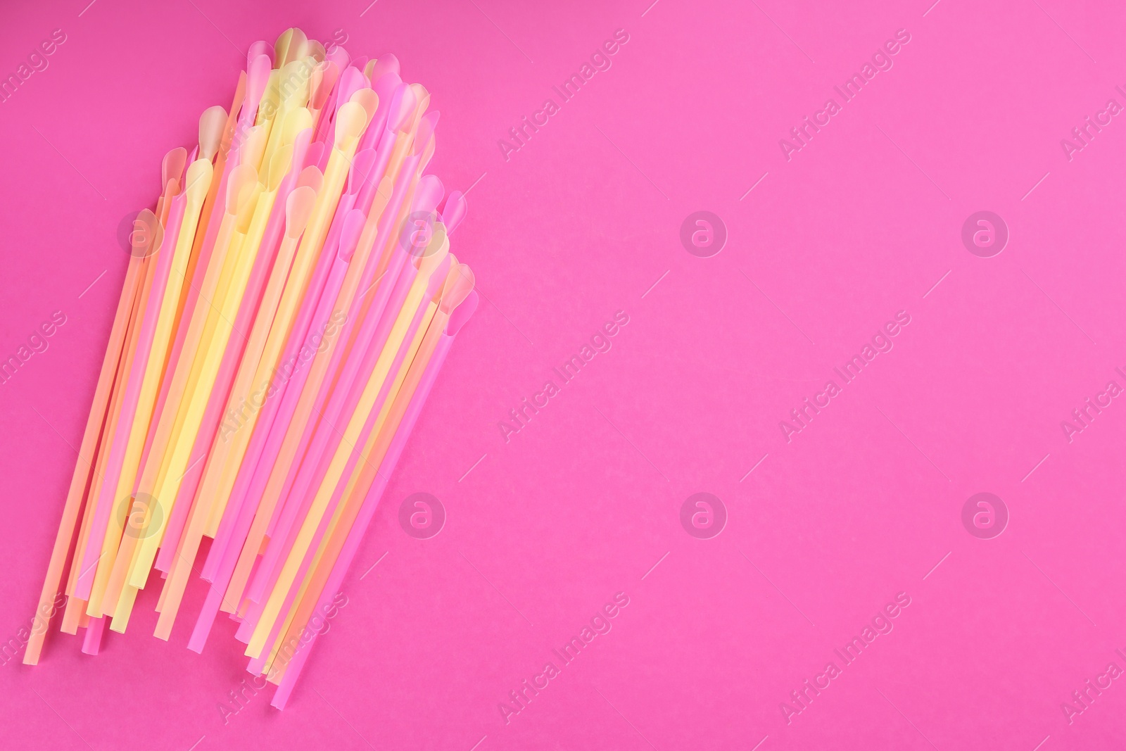 Photo of Colorful plastic drinking straws on pink background, flat lay. Space for text