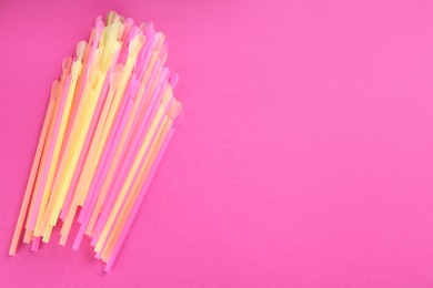 Colorful plastic drinking straws on pink background, flat lay. Space for text