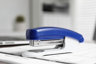 Stapler and document on table indoors, closeup