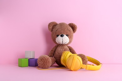 Baby songs. Toy bear, headphones and cubes on pink background