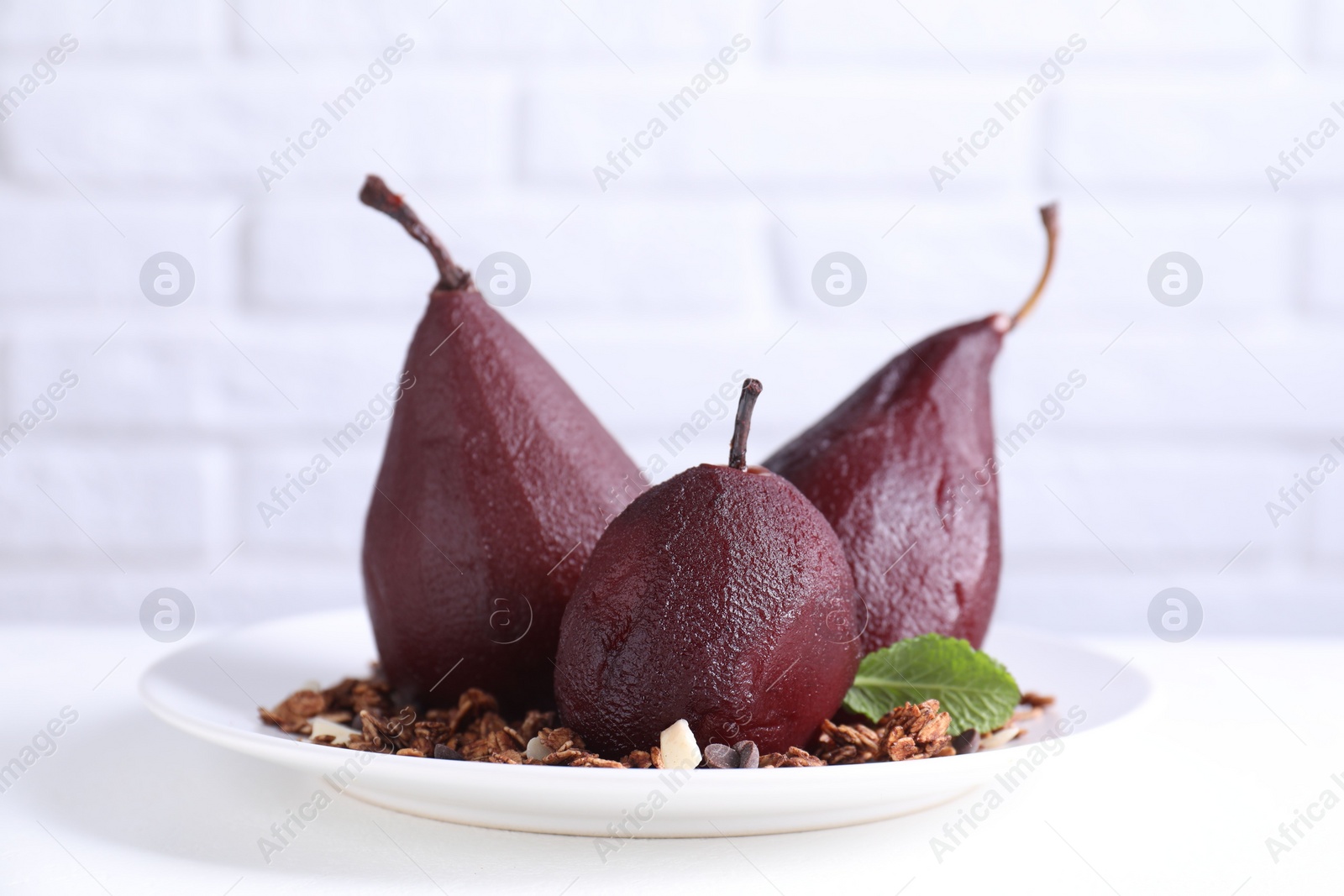 Photo of Tasty red wine poached pears with muesli on white table, closeup