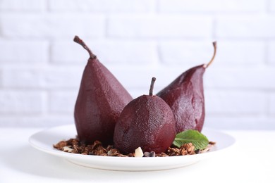 Tasty red wine poached pears with muesli on white table, closeup