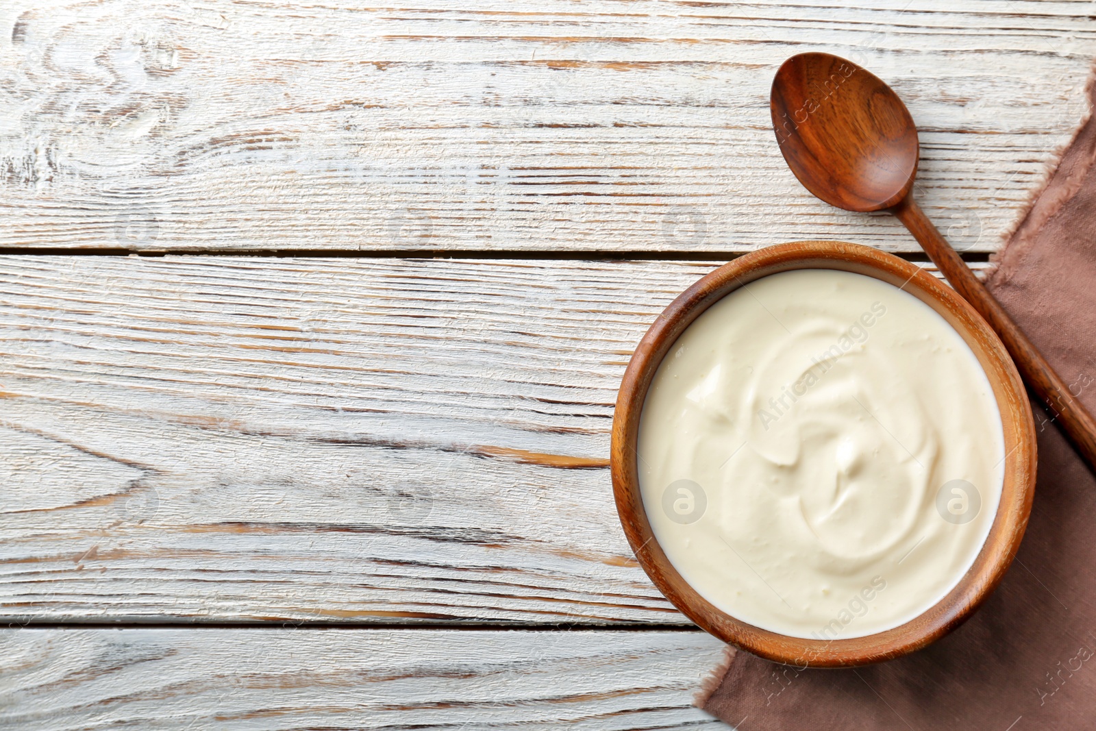 Photo of Bowl with tasty yogurt on wooden background