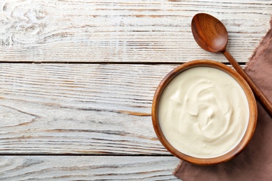 Bowl with tasty yogurt on wooden background