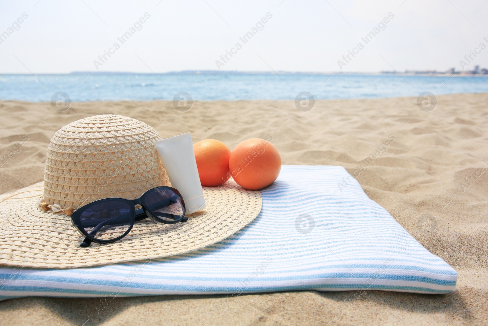 Photo of Beach accessories and oranges on sand near sea. Space for text