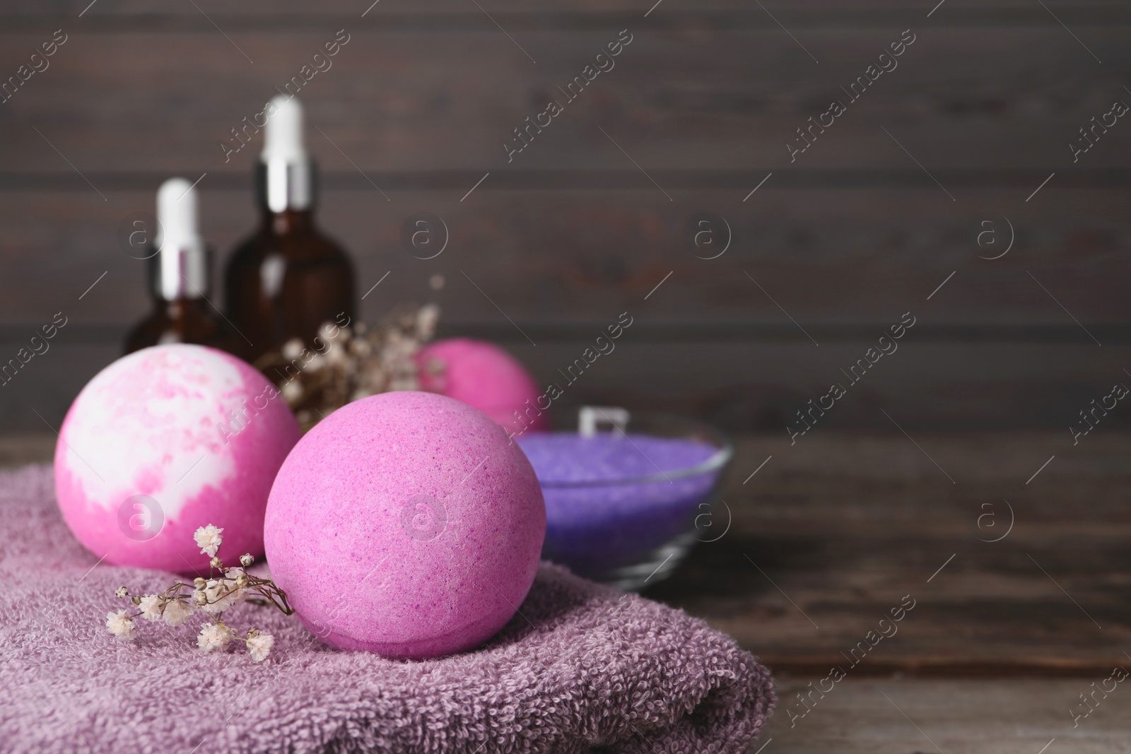 Photo of Beautiful aromatic bath bombs, gypsophila flowers and soft towel on table, closeup. Space for text