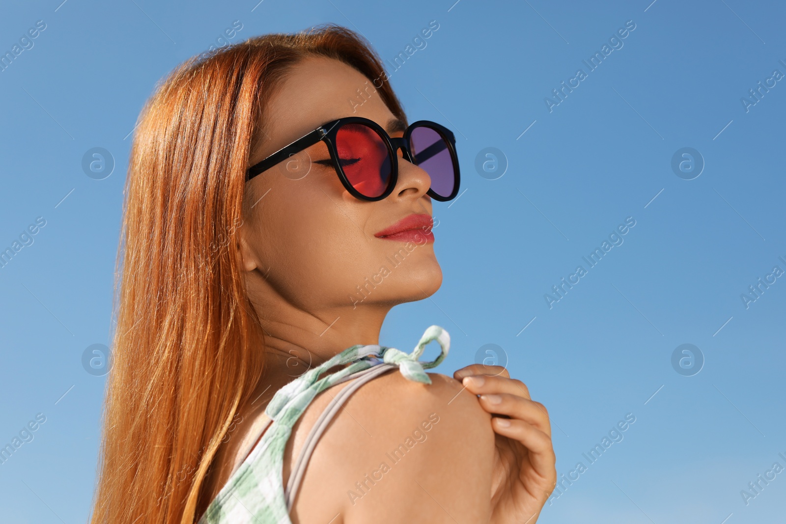 Photo of Beautiful woman in sunglasses against blue sky, space for text