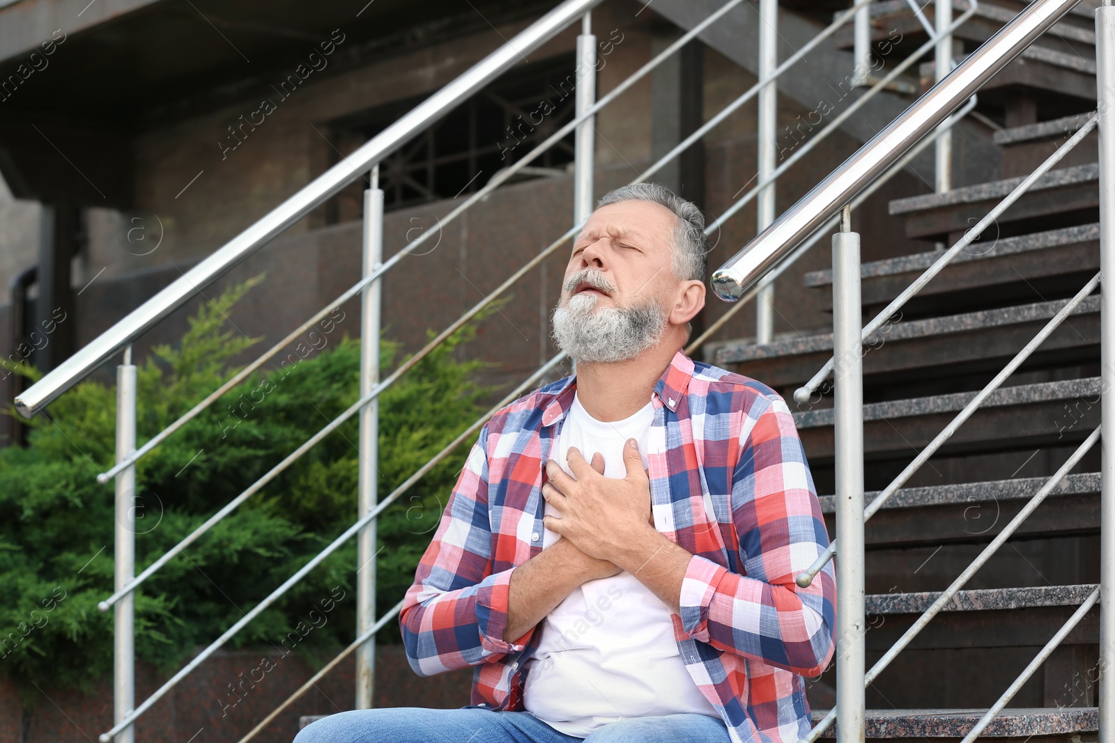 Photo of Mature man having heart attack on stairs, outdoors