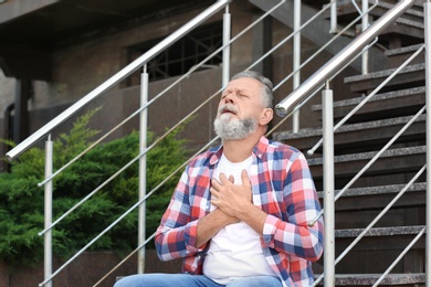 Photo of Mature man having heart attack on stairs, outdoors