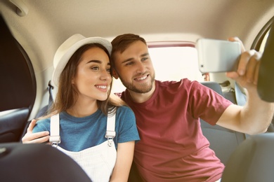 Photo of Happy young couple taking selfie in car