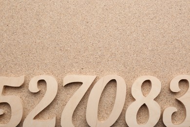 Photo of Wooden numbers on fiberboard, flat lay. Space for text