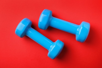 Photo of Bright dumbbells on color background, flat lay. Home fitness