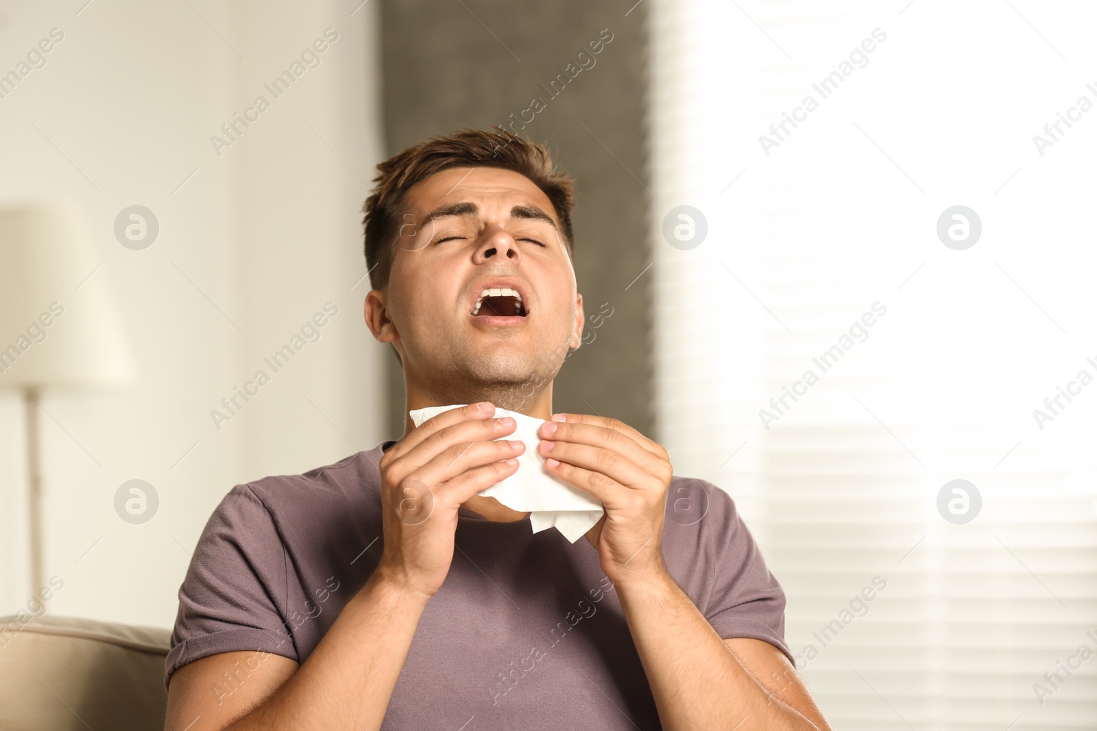 Photo of Young man suffering from allergy at home