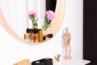 Photo of Stylish round mirror and dressing table with accessories indoors. Interior design